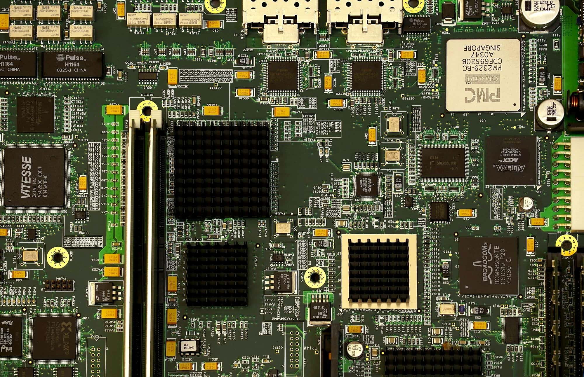 Top-down view of a densely populated circuit board with heatsinks and fine-pitch components
